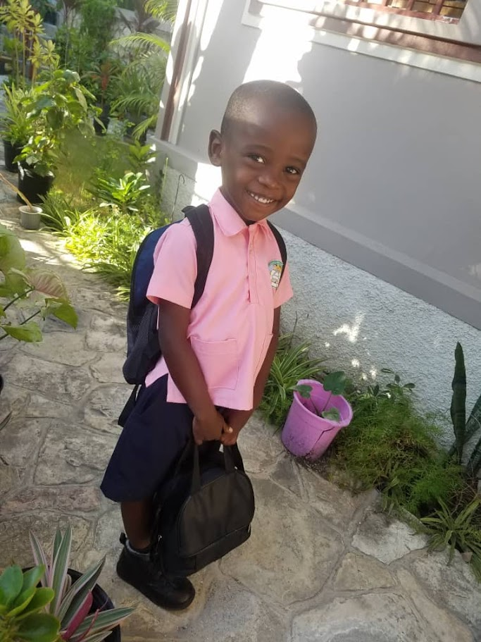 Young boy in school uniform with backpack, supported by the Simone J Williams Scholarship Fund